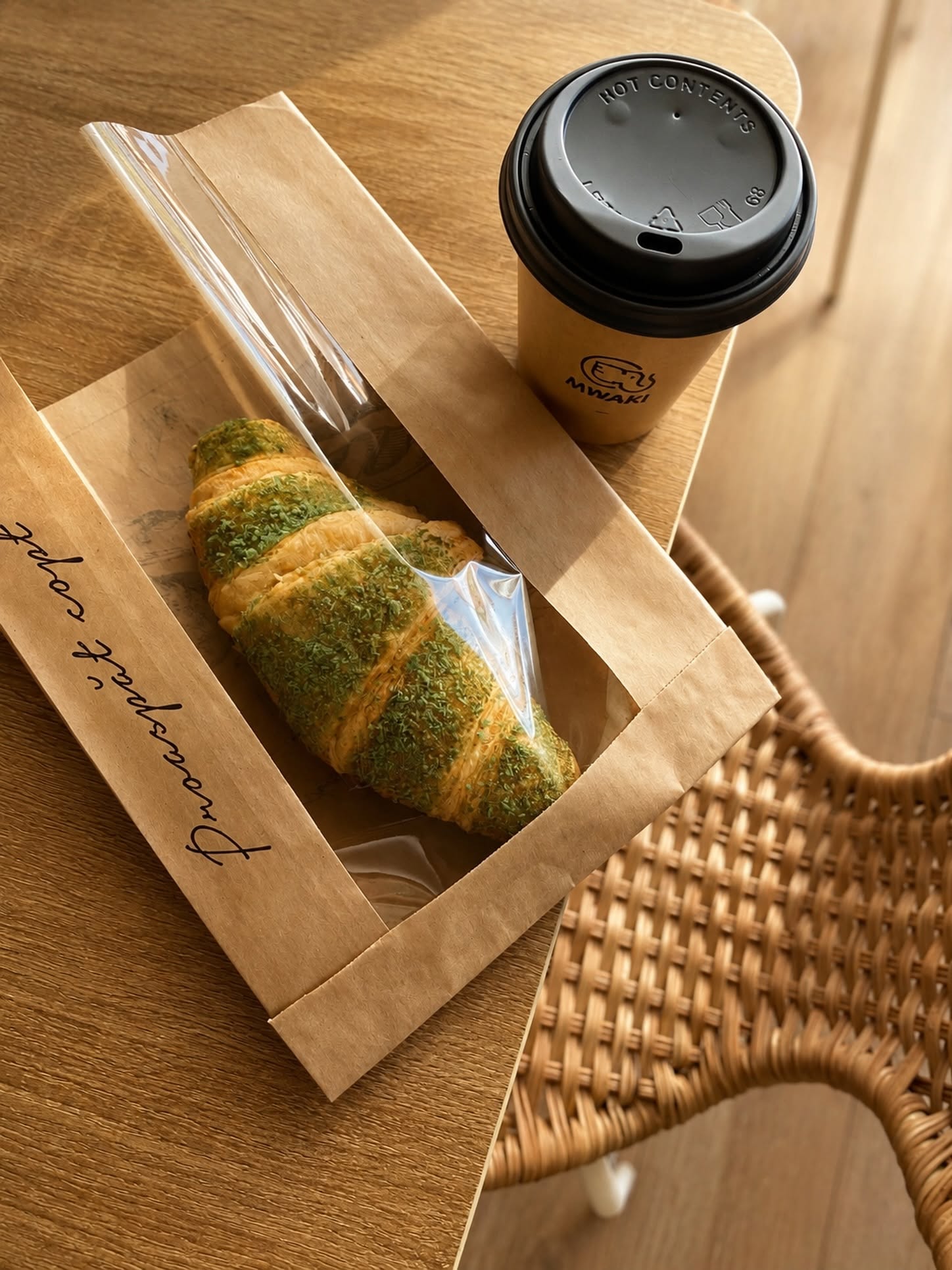 Croissant cu fistic și cafea MWAKI la pachet, pe o masă din lemn
